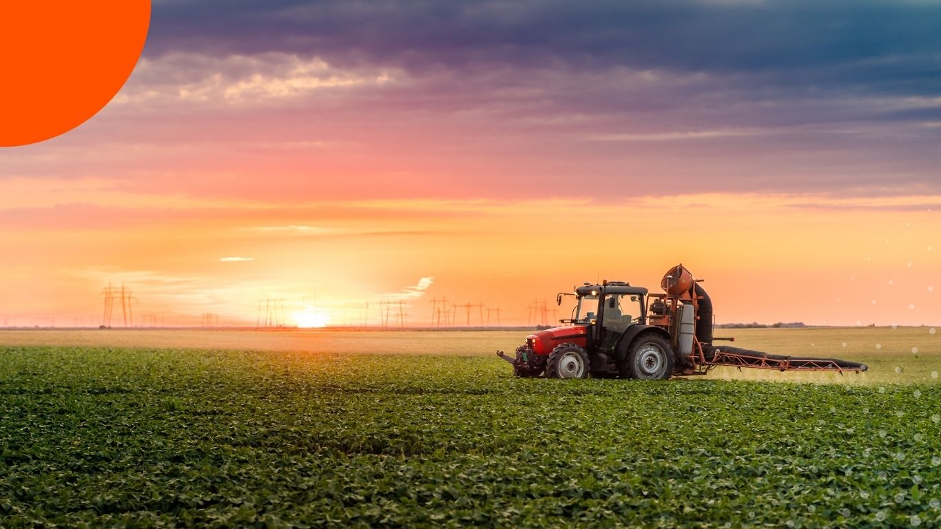 A tractor working agricultural fields at sunset