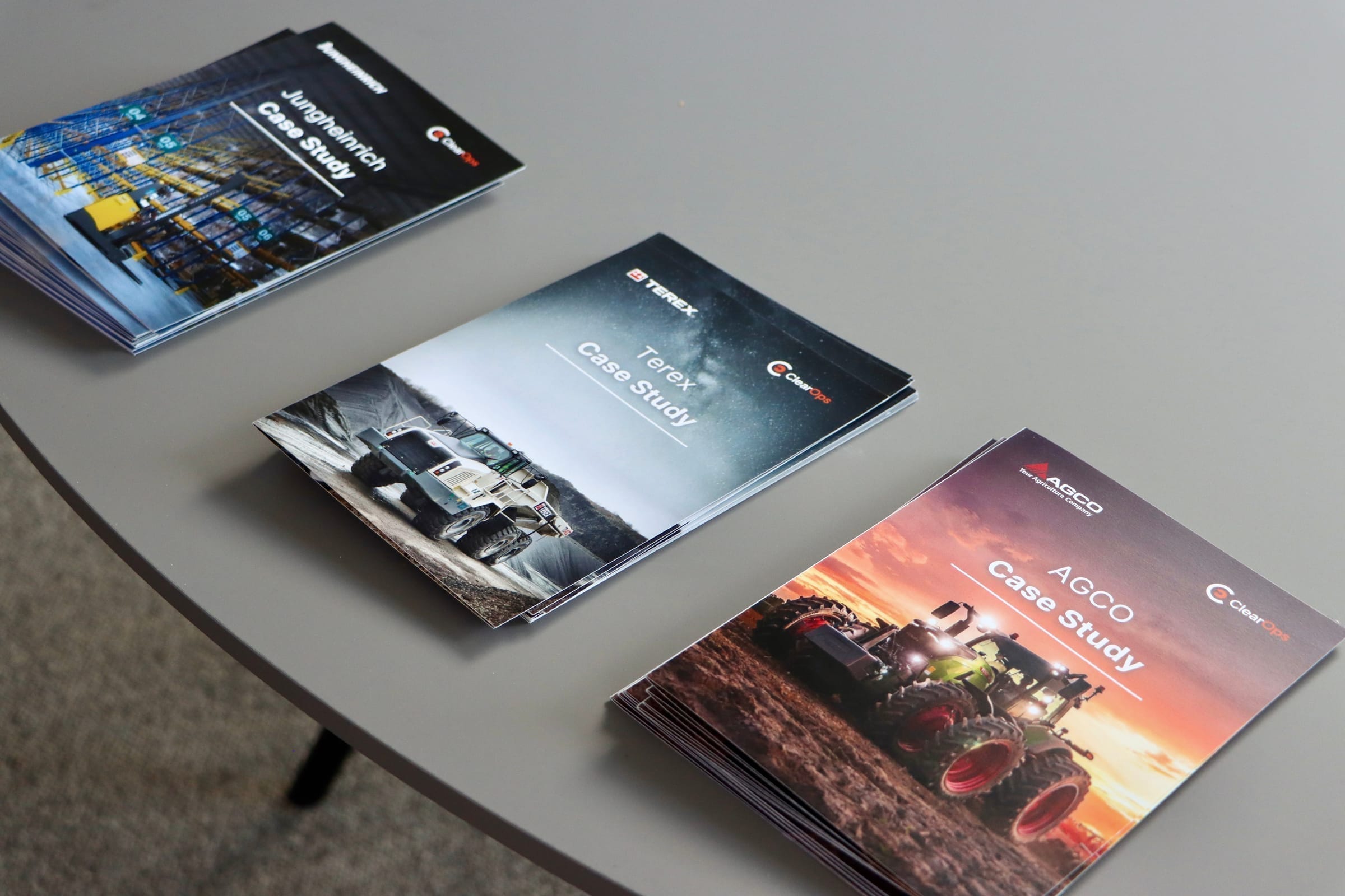 Printed ClearOps case study flyers featuring AGCO, Terex, and Jungheinrich